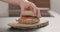 Man hands put top on salmon on ciabatta with cream cheese to make a sandwich on wood board