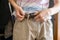 Man hands puts on casual trousers pants or shorts and tight belt close up f