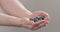 Man hands show wet washed ripe blueberries on neutral background