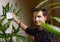 Man hands showing surgical mask on green plants, man holding surgical mask and giving nice smile.