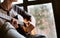 Man hands sitting on the big window windowsill and playing on guitar - fingers close up image