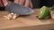 Man hands slice lemon grass in pieces on cutting board with other Thai herbs beside for Tom Yum recipe.
