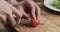 Man hands slicing cherry tomato on wooden board