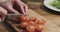 Man hands slicing cherry tomato on wooden board