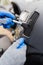 Man hands wearing protective gloves using cleaning brush and removing dust from car air conditioning vent grill. Car detailing or