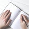 Man hands writing notes to the notebook on wooden table in home office