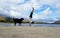Man Handstands on beach with black dog next to him in Hawaii Kai