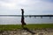 Man Handstands on rocky grassy beach with Pier