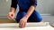 A man, a handyman in a blue jumpsuit, is assembling a table in close-up. He baits the screws into the table frame.