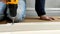 A man, a handyman in a blue jumpsuit, is assembling a table in close-up. He gathers the table frame with a screwdriver