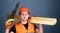 Man, handyman in helmet, hard hat holds handsaw and wooden beams, grey background. Carpenter, woodworker, labourer