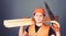 Man, handyman in helmet, hard hat holds handsaw and wooden beams, grey background. Carpenter, woodworker, labourer