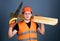 Man, handyman in helmet, hard hat holds handsaw and wooden beams, grey background. Woodcraft concept. Carpenter