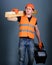 Man, handyman in helmet, hard hat holds toolbox and wooden beams, grey background. Carpenter, woodworker, labourer