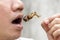 Man happy opening his mouth eating Crickets insect on wooden skewer. Food Insects for eat as food items, it is good source of meal
