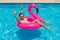 Man has fun on a fuchsia flamingo inflatable float in the pool