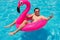 Man has fun on a fuchsia flamingo inflatable float in the pool