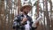 Man in a hat holds a map in and looks through binoculars while hiking