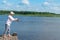 A man with a hat takes part in a spinning fishing competition on the river bank