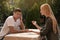 Man having boring date with talkative woman in outdoor cafe