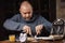 The man is having breakfast. An ordinary middle-aged man in a sweater is preparing to eat a sandwich in a dark room