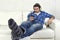 Man having fun alone lying on couch listening to music with mobile phone and headphones
