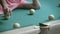 A man is having fun lying on a billiard table, rolling a billiard ball into a pocket with his hand