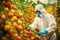 Man in hazmat suit and respirator sprays tomatoes against pests. Generative AI