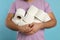 Man with heap of toilet paper rolls on light blue background, closeup