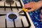 A man heats a nail over a gas stove fire to make a hole in a flower pot