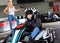 Man in helmet driving car for karting in sport club, woman with flag on background