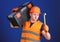 Man in helmet, hard hat carries toolbox and holds hammer, blue background. Handyman concept. Worker, repairer, repairman