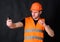 Man in helmet, hard hat taking selfie photo, dark background. Worker, contractor, builder on strict face holds