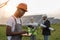 Man in helmet and overalls typing on laptop at solar farm