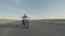 Man in helmet and sunglasses rides motorbike on road, front view. Biker on motorcycle rides highway during day in steppe