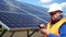 Man in helmet using smartphone on the background of solar panels. Solar power plant worker male portrait.