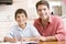 Man helping young boy in kitchen doing homework an