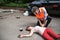 A man helping a young woman lying unconscious on the road after a car accident.