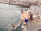 A man helps a girl to climb the pier from the sea