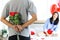 Man hiding beautiful red rose bouquet behind back, ready to give Valentine flower present to lover girlfriend for celebration,