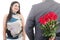 Man hiding bunch of red roses behind his back to surprise