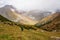 Man hiker with backpack looking at rainbow. Male Backpacker in rainy mountains Karakol valley on trail to Ala Kul lake. Karakol