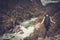 Man hiker with backpack standing on the edge of the cliff with epic wild mountain river view.