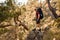 man hiker with backpack stands on large stone among the trees