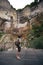 A man, a hiker, a backpacker, stands and looks at a Kinchkha waterfall. Georgia. Vertical photo