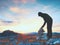 Man hiker is building pebbles pyramid. Stones on Alps mountain summit. Daybreak horizon