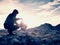 Man hiker is building pebbles pyramid. Stones on Alps mountain summit. Daybreak horizon