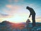 Man hiker is building pebbles pyramid. Stones on Alps mountain summit. Daybreak horizon