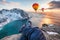 Man hiker cross legs sitting on rock ridge with hot air balloon flying on ocean