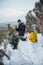 Man hiker have a rest at mountain top, drinking tea and eating during winter adventure.